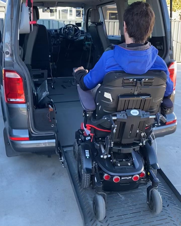 Person wearing a blue top is going into the back of a van in a power wheelchair.
